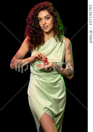 Smiling gambling young woman holding red betting tokens 107146765