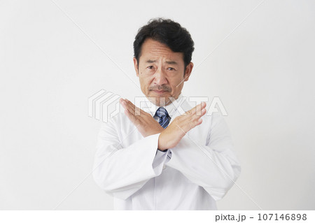 腕でばつ印をする中年の医師 白背景 腕でばつ印をする中年の医師 白背景 107146898