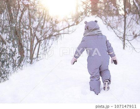 A little girl is walking in the park on the snow winter day. 107147911