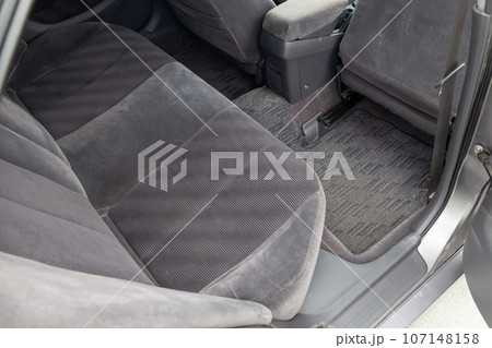 Close-up on rear seats with velours fabric upholstery in the interior of an old car in gray after dry cleaning. Auto service industry 107148158