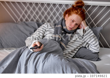focus on remote control, angry depressed girl is tired to watch TV focus on remote control, angry depressed girl is tired to watch TV 107149821