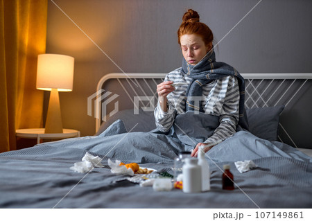 sleepy depressed girl checking her high temperature in bedroom sleepy depressed girl checking her high temperature in bedroom 107149861