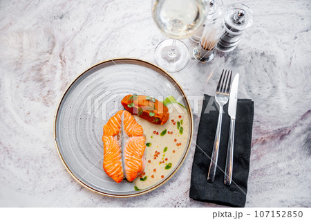Salmon fillet in cream sauce with herbs on a marble table in a restaurant Salmon fillet in cream sauce with herbs on a marble table in a restaurant 107152850