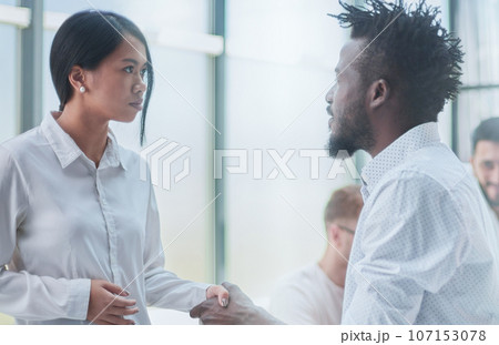 Business Handshake - business people shaking hands. Handshake between business man and woman indoors. Business Handshake - business people shaking hands. Handshake between business man and woman indoors. 107153078