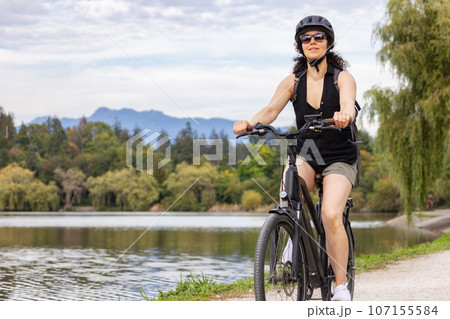 Fit Caucasian Woman riding an Electric Bicycle on a trail in Stanley Park, Downtown Vancouver, British Columbia, Canada 107155584