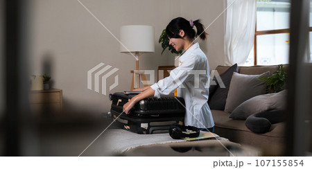 Young asian woman traveler pack bags prepare for the travel season vacation, concept lifestyle active journey and trip travel Young asian woman traveler pack bags prepare for the travel season vacation, concept lifestyle active journey and trip travel 107155854