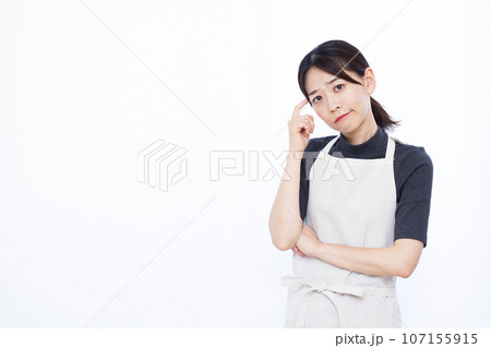 白い背景の前で真剣に悩んでいる30代の主婦 白い背景の前で真剣に悩んでいる30代の主婦 107155915