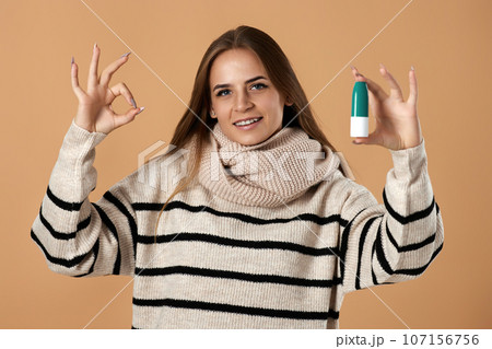 woman holds nasal spray for allergies on beige background 107156756