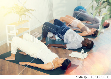 Young woman practicing pilates in group in studio Young woman practicing pilates in group in studio 107157864