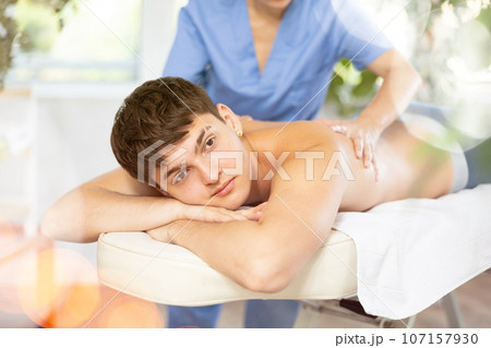 Female masseuse makes relaxing massage shoulder zone to man in beauty parlor 107157930