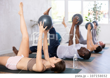 Pilates - women and men with soft ball pilates at gym Pilates - women and men with soft ball pilates at gym 107158032