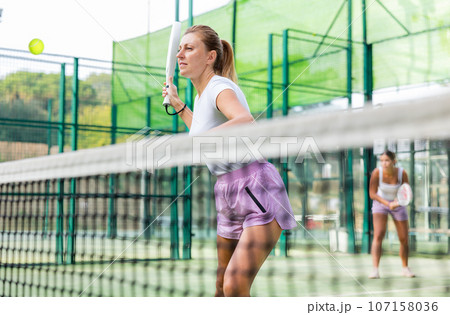 European woman padel tennis player trains on the outdoor court European woman padel tennis player trains on the outdoor court 107158036