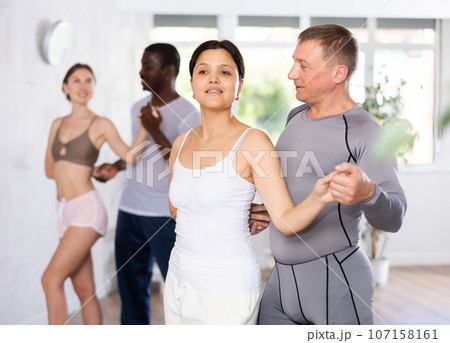 Group of multiethnic active people dancing dance movements in studio Group of multiethnic active people dancing dance movements in studio 107158161