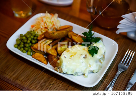 Veal Orloff with potato wedges, green peas and cabbage salad Veal Orloff with potato wedges, green peas and cabbage salad 107158299