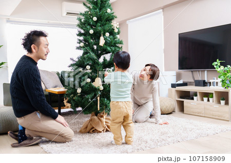クリスマスツリーの飾り付けをする家族 107158909