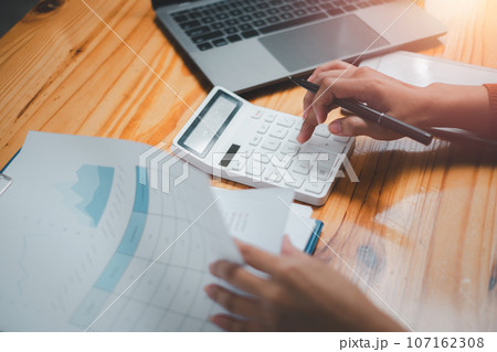 Close up Businesswoman using calculator, managing household monthly budget, summarizing taxes or bills, planning future investments, accounting bookkeeping concept. 107162308