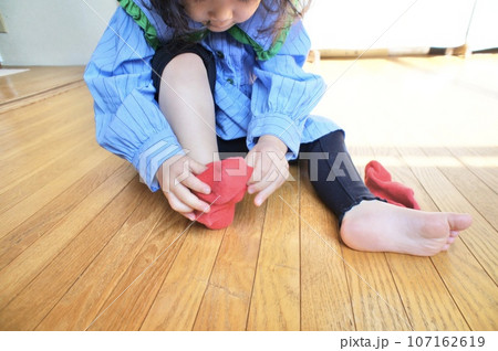自分で赤い靴下を履く小さな女の子 自分で赤い靴下を履く小さな女の子 107162619