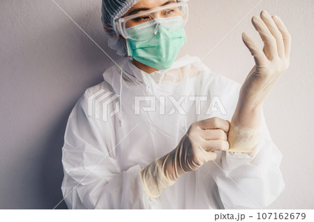 Healthcare worker wearing safety glove and PPE suit for working in hospital during Covid-19 pandemic. PPE is equipment that will protect the user against health or safety risks at work. 107162679