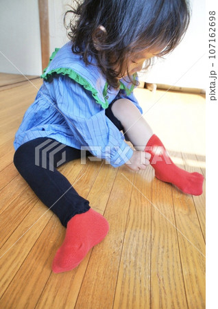 自分で赤い靴下を履く小さな女の子 自分で赤い靴下を履く小さな女の子 107162698
