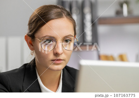 Close-up businesswoman freelancer at office workplace works on laptop computer sends online messages 107163775