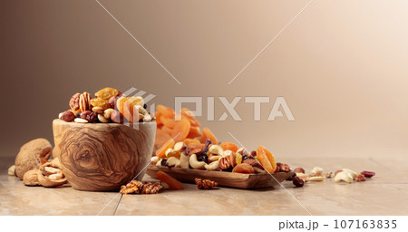 Dried fruits and nuts on a beige ceramic table. Dried fruits and nuts on a beige ceramic table. 107163835