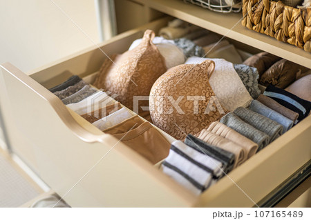 Modern wardrobe with stylish women's clothing. Drawer with underwear, t-shirts, socks and shorts. The concept of storage and order. 107165489