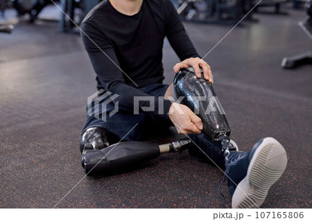 guy in stylish sportswear taking off his prosthetic leg guy in stylish sportswear taking off his prosthetic leg 107165806