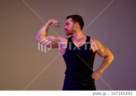 Muscular motivated ambitious young man shows his strength Muscular motivated ambitious young man shows his strength 107165892