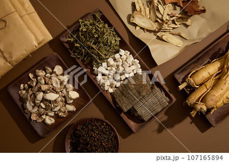 Many different types of herbal medicine are featured on paper and wooden dishes. Brown background. These herbs helps get more energy and treat skin diseases Many different types of herbal medicine are featured on paper and wooden dishes. Brown background. These herbs helps get more energy and treat skin diseases 107165894