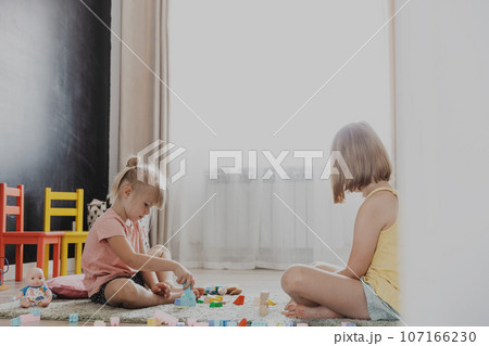Children playing with toy building blocks on the floor at home or kindergarten 107166230