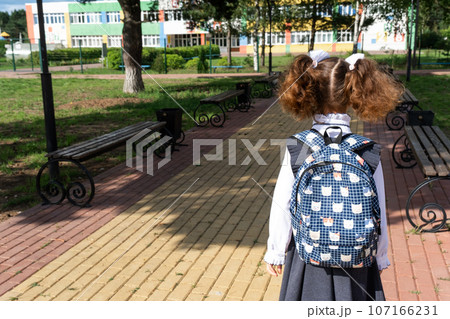 Pupil with backpack and in a school uniform in school yard back to the frame. Back to school, September 1. A happy student. Primary education, elementary class. Road to life, to knowledge Pupil with backpack and in a school uniform in school yard back to the frame. Back to school, September 1. A happy student. Primary education, elementary class. Road to life, to knowledge 107166231