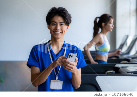 スマホを持つスポーツジムのトレーナー 107166640