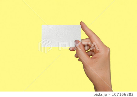 Female Hand Holding White Business Card Isolated On Yellow Studio Background. Close Up. Visiting Card Template, Mock Up. Woman's Hand with Plastic Gift Card MockUp Isolate. Advertisement gesture. Female Hand Holding White Business Card Isolated On Yellow Studio Background. Close Up. Visiting Card Template, Mock Up. Woman's Hand with Plastic Gift Card MockUp Isolate. Advertisement gesture. 107166882