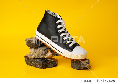 New black and white canvas sneakers on yellow background 107167800