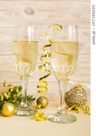 Champagne glasses and christmas decor on colored holiday background. Flat lay New Year decorations Champagne glasses and christmas decor on colored holiday background. Flat lay New Year decorations 107169285