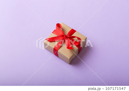 Wrapped christmas or other holiday handmade present in craft paper with colored ribbon. Present box, decoration of gift on table, top view with copy space Wrapped christmas or other holiday handmade present in craft paper with colored ribbon. Present box, decoration of gift on table, top view with copy space 107171547