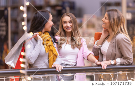 Three happy female friends are talking about their purchases in the mall Three happy female friends are talking about their purchases in the mall 107171739