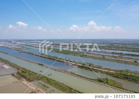 Aerial view of natural sea salt ponds, lake or sea. Farm field outdoor in traditional industry in Thailand. Asia culture. Agriculture irrigation. River reflection. 107173185
