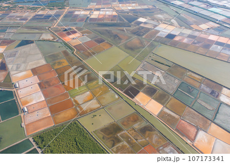 Aerial view of natural sea salt ponds, lake or sea. Farm field outdoor in traditional industry in Thailand. Asia culture. Agriculture irrigation. River reflection. 107173341