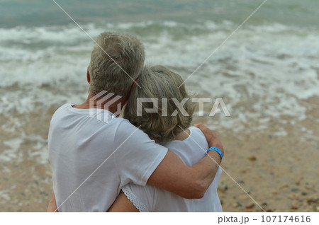 silhouette rear view of asian elderly couple standing on the beach and chatting happily in sunrise silhouette rear view of asian elderly couple standing on the beach and chatting happily in sunrise 107174616