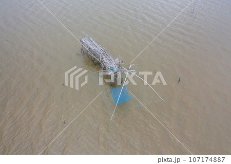 Aerial view of fishing trap net in canel with fisherman urban city village town houses, lake or river. Nature landscape fisheries and fishing tools at Pak Pha, Songkhla, Thailand. Aquaculture farming 107174887