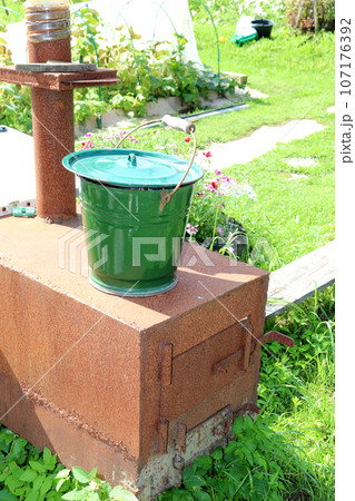A metal bucket stands on a homemade cast iron stove in the garden 107176392