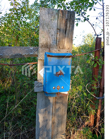 Abandoned old rusty Russian metal mailbox on a destroyed fence 107176393