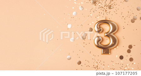 Gold candle in the form of number three. 107177205