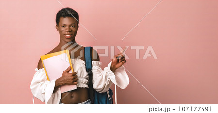 Smiling transgender student with notebooks pointing away Smiling transgender student with notebooks pointing away 107177591