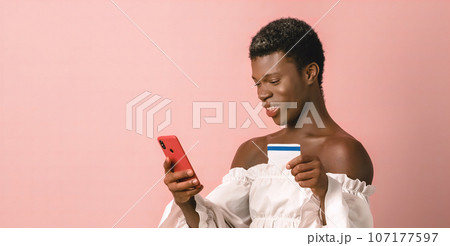 African transgender person using a mobile phone and a credit card. African transgender person using a mobile phone and a credit card. 107177597