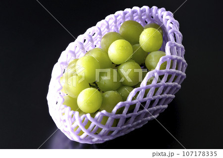 フルーツキャップに入っているシャインマスカットを黒背景で撮影 107178335