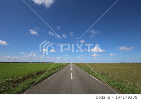 北海道最北の地、オホーツクを望む牧草地の一本道、その名は猿払村道エサヌカ線、夏の空に映えるツーリング 107179339