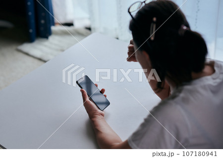 スマホを持ち眉間を押さえるシニア女性 スマホを持ち眉間を押さえるシニア女性 107180941