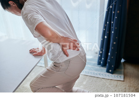腰の痛みをこらえながら立ち上がるシニア女性 107181504